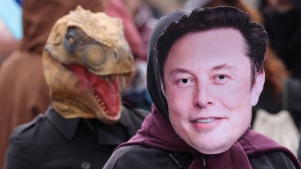 An activist dressed as Elon Musk is trailed by a fellow activist dressed as a fossil fuel lobby dinosaur during a demonstration by the environmental action and human rights group Extinction Rebellion.