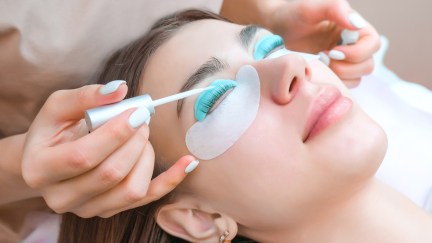 Young woman receiving eyelash lamination procedure in a beauty salon, close up