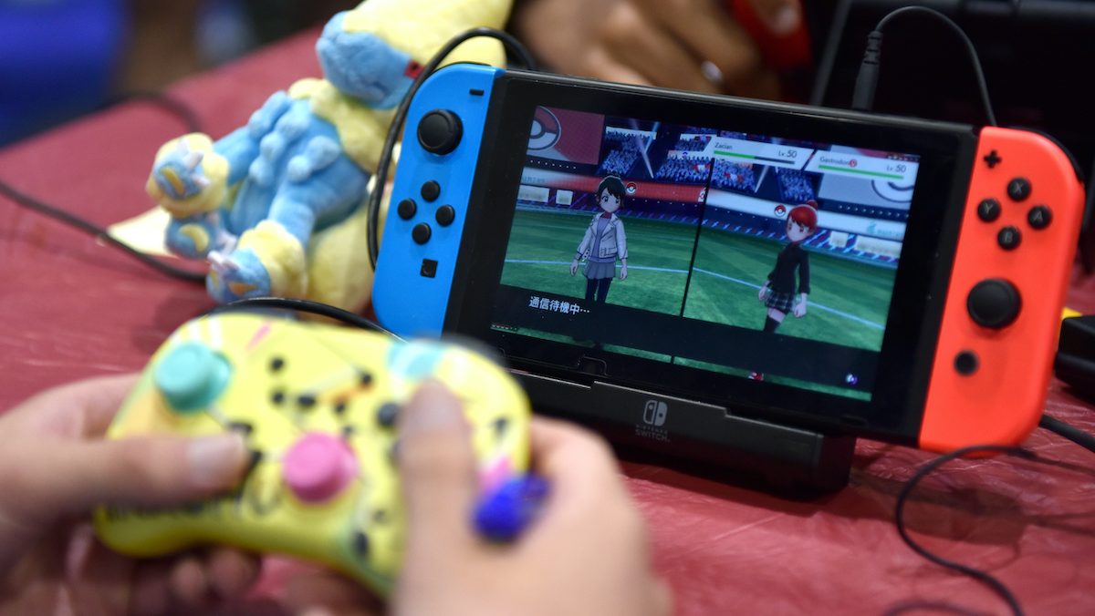 Close up of hands playing a Nintendo Switch via a separate controller.