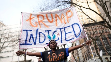 A Black woman holds a giant banner reading 