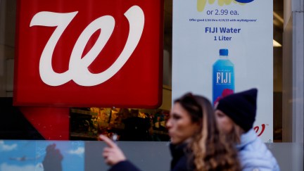 People walking by the window of a Walgreens store.