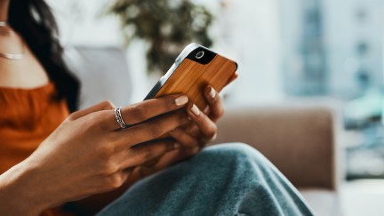 A woman with her face obscured looks at her cell phone