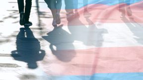 Transgender flag fades into shadows and silhouettes of people on a road