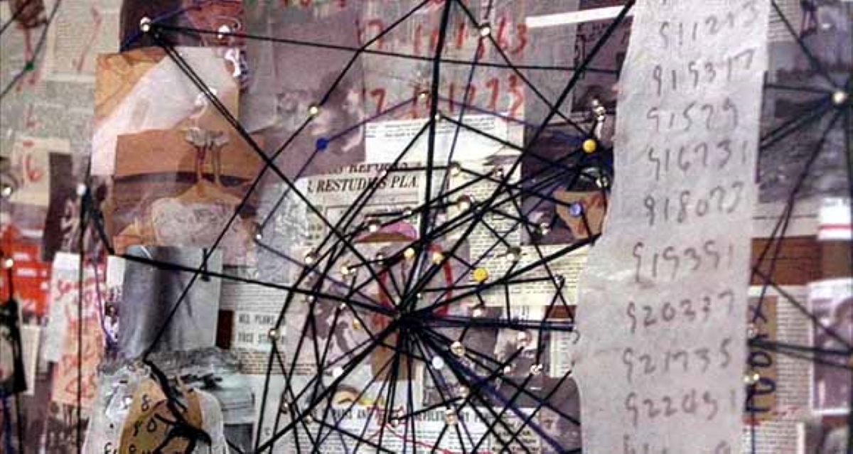 In a scene from A Beautiful Mind, papers and news clippings cover a wall, connected by a web of string.