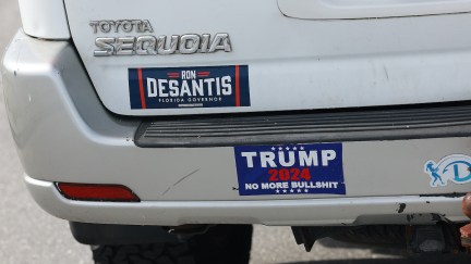 A Florida Gov. Ron DeSantis sticker and one reading, 'Trump 2024 No More Bullshit', are displayed on a white car.