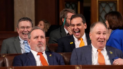 George Santos and some other Republicans sit and laugh.