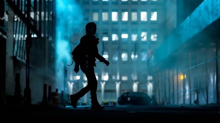 A silhouette walks through a city at night in The Walking Dead: Dead City.