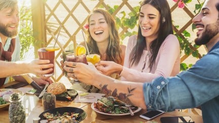 A group of white early-30s friends cheers over brunch.