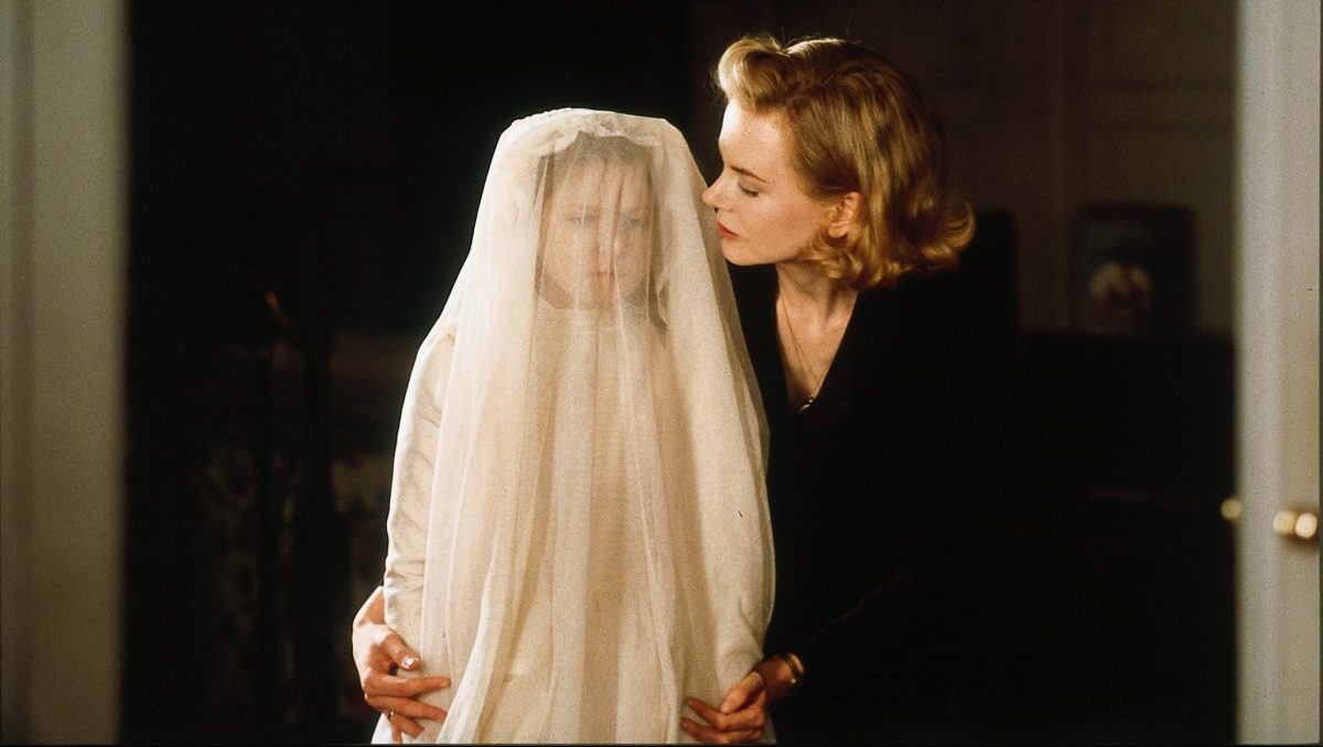 Nicole Kidman as Grace in "The Others" standing over a small child with a long white veil over it's face.