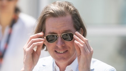 Wes Anderson adjusting his sunglasses.