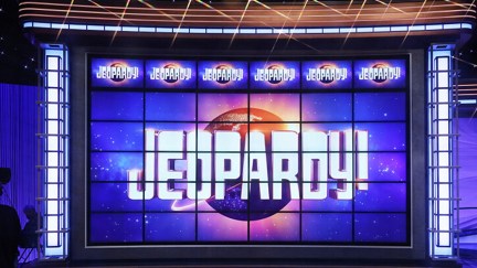 Image of the 6x6 grid of screens that make up the question board on the set of 'Jeopardy!' There are no questions or categories on the screens. The top six screens feature the 'Jeopardy!' logo in each one, and the rest of the screens each contain an image that add up to one larger 'Jeopardy!' logo.