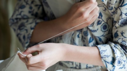 A colonial actor in Williamsburg Virginia shows her sewing technique