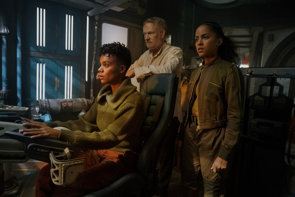 Salvor, Gaal, and Hari stand in a ship's cockpit, looking tense. From Foundation.