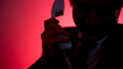 Silhouette of man making a phone call against a dramatic red background.