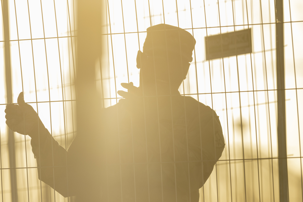 The silhouette of a border agent at a wire fence.