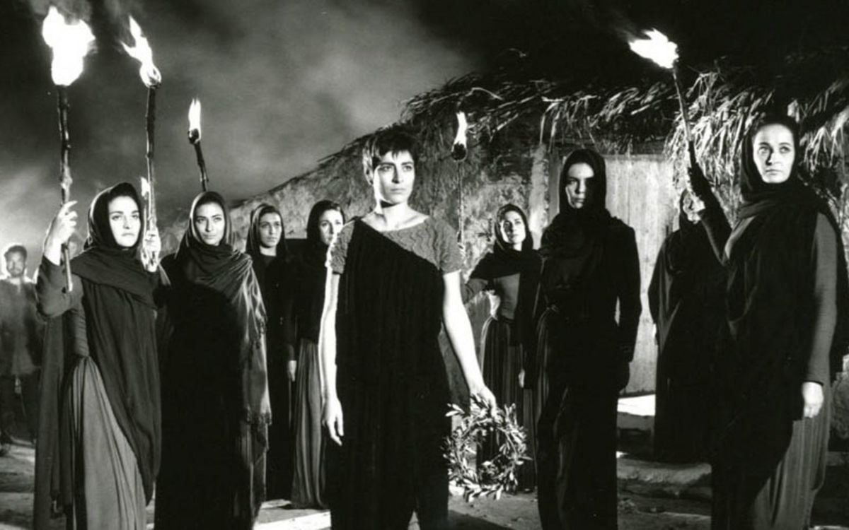 A group of women in black togas stand outside while holding torches in "Electra"