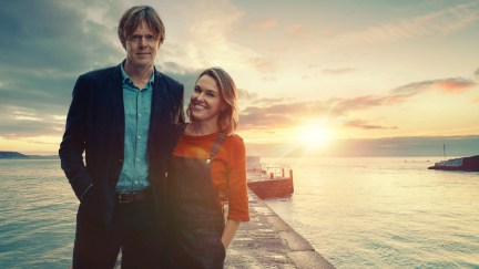 Kris Marshall as DI Humphrey Goodman and Sally Bretton as Martha Lloyd in Beyond Paradise, standing in front of a sunset