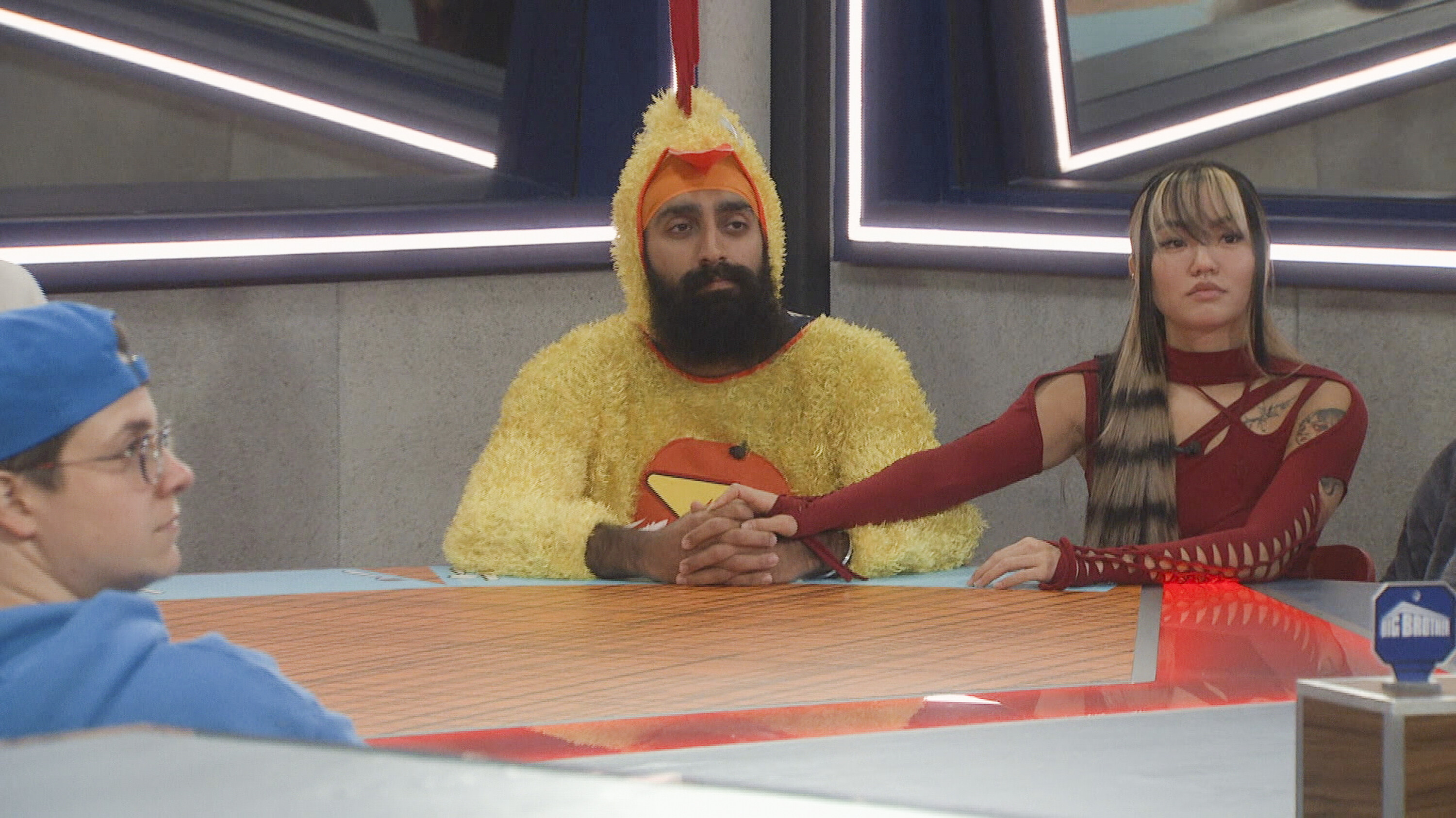 Big Brother contestants dressed in costumes look tense.