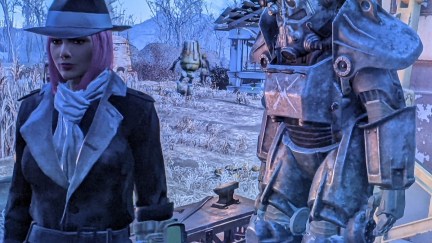 Screencap from the game 'Fallout 4.' Teresa Jusino's female player character is dressed in the Silver Shroud black trench coat and hat and has brown skin and a pink, chin-length bob. She's standing next to her Minuteman Power Armor at Sanctuary settlement.