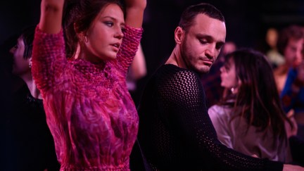 Agathe and Tomas dancing in pink hued lighting in the film 