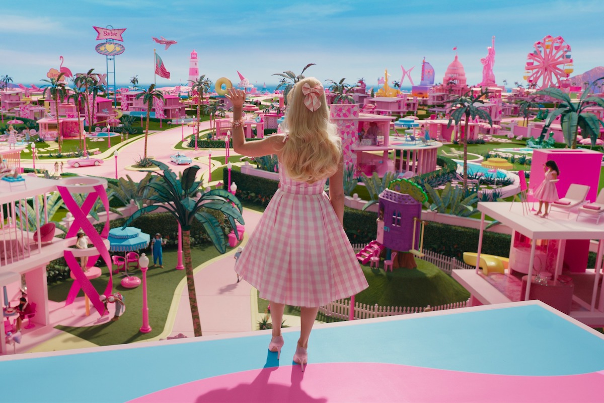 In a scene from Barbie, Barbie is seen from behind, waving to Barbieland from her balcony