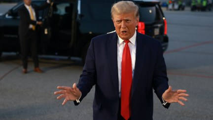 Donald Trump gestures and speaks to reporters outside.