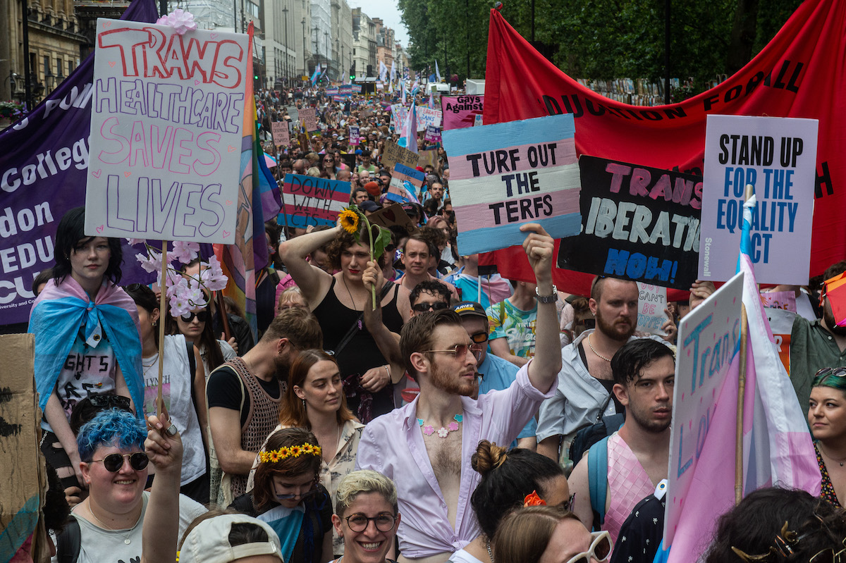 A trans rights rally featuring a large crowd of marching protesters.