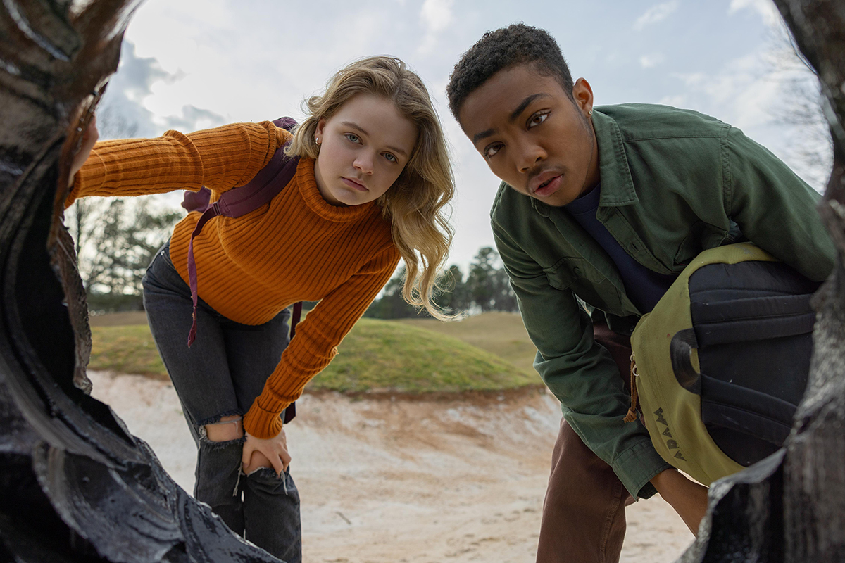 Two kids looking into a hole in Landscape With Invisible Hand