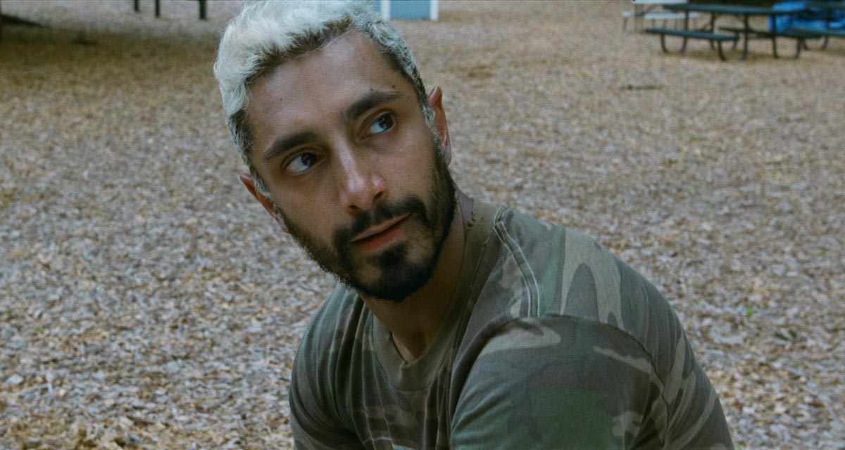 Riz Ahmed sitting on the ground in a camo shirt in The Sound of Metal 