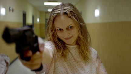 Heather Graham wears a hospital gown while holding a gun and smiling in the new horror movie 'Suitable Flesh'