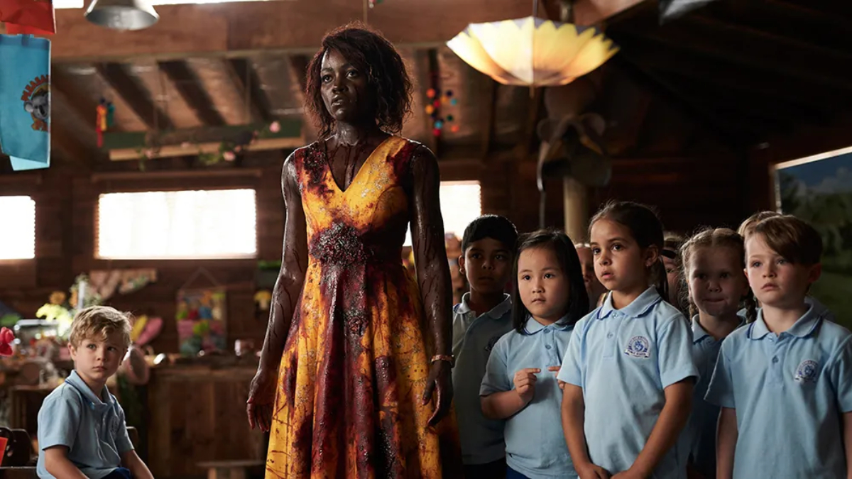 A bloody Miss Caroline (Lupita Nyong'o) surrounded by her young students in 'Little Monsters'