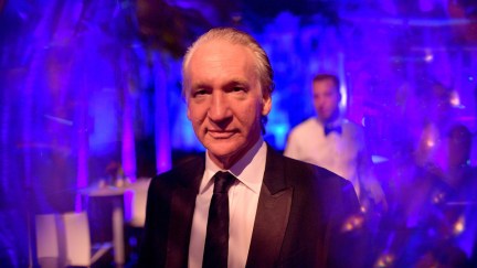 Bill Maher at a party with a purple lighting effect around him.