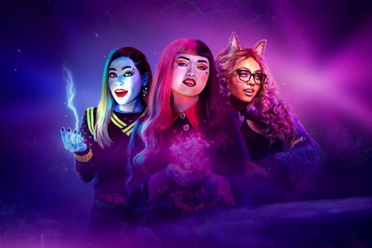 A promotional image from Monster High 2; Ceci Balagot, painted pale blue with long dark hair, Naya Damasen, painted pink with pink and black hair, and Miia Harris, with long reddish brown curls and wolf ears, all stand next to each other. Their torsos fade out against the purple, misty background.