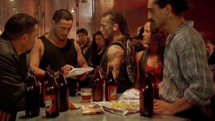 Jake, Beth, and others standing around a bar table in 'Once Were Warriors'.