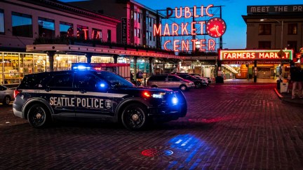 A police car sits in front of Seattle's Public Market at night.