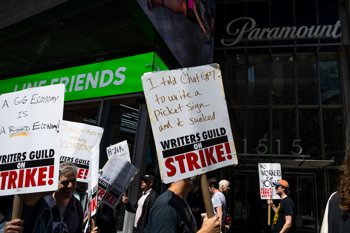 NEW YORK, NEW YORK - MAY 17: Writers Guild of America (WGA) East members walk a picket line at the Paramount+ Summit outside the Paramount Building in Times Square on May 17, 2023 in New York City. As the strike enters its third week the WGA East members picketed at events centered around New York Upfront week, a decades-old tradition where media companies stage lavish events to promote their new programming lineups in an attempt to woo advertisers. Union members have stated that they are not being paid fairly in the streaming era and are seeking pay increases and structural changes to the business model. Many are also concerned about the effects of AI across the industry. (Photo by Alexi Rosenfeld/Getty Images)