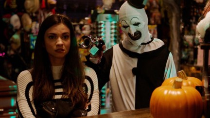 Sienna (Lauren LaVera) and Art the Clown (David Howard Thornton) stand next to each other in a Halloween store in a scene from Terrifier 2