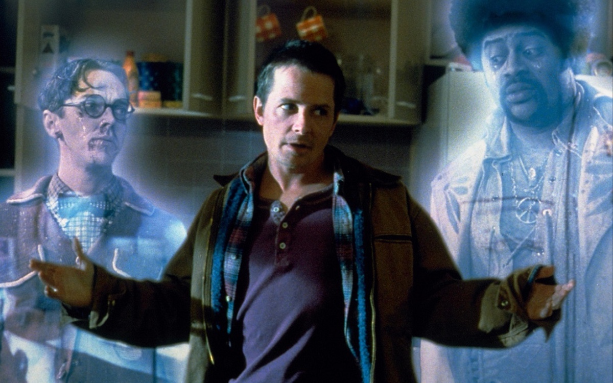 Michael J. Fox as Frank Bannister in The Frighteners; he's a caucasian man wearing a maroon long-sleeve henley under a plaid vest and green vest