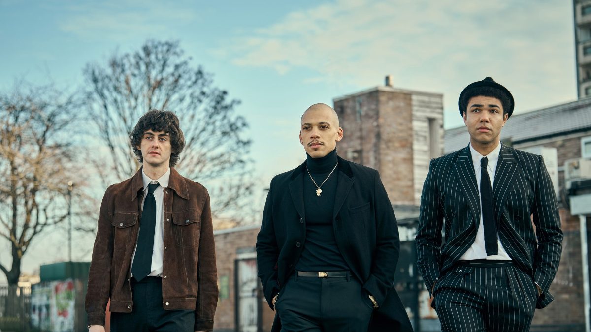 Three men wearing ska clothes walk down a street in 'This Town.'