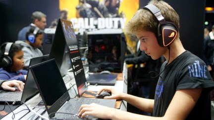 A young gamer plays a Call of Duty game on a laptop.