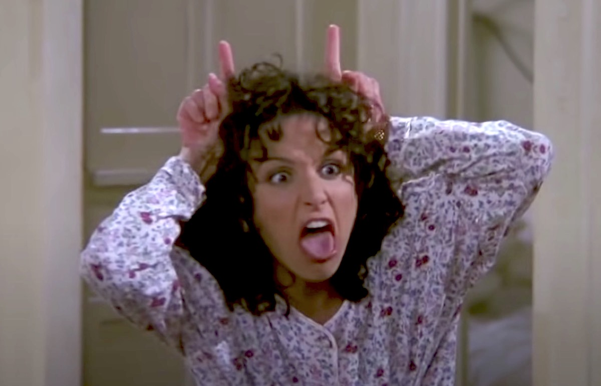Elaine makes mocking devil horns on her head in Seinfeld.