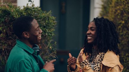 David Jonsson as Dom and Vivian Oparah Yas in 'Rye Lane' laughing with each other outside a house.