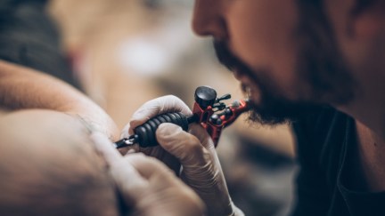 Artist making tattoo on customer's hand in studio