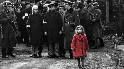 A little girl in a red coat walks in front of soldiers in the film 'Schindler's List'