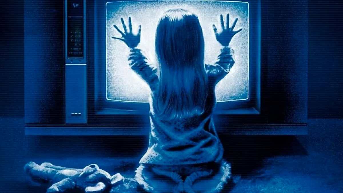 child holding hands up to television screen that has static on it