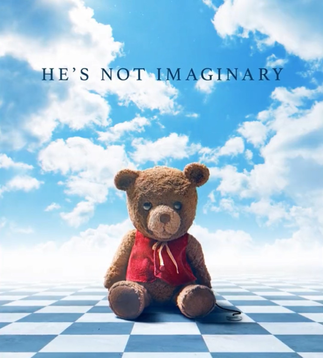 sad teddy bear sitting on a checkerboard floor with blue sky above him