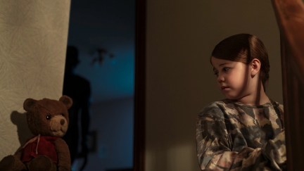 Pyper Braun in 'Imaginary,' a new horror movie from Blumhouse: a girl looks disconcertingly at a teddy bear while a dark figure lurks in the background