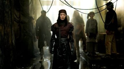 Bae Doona as Nemesis stands in an industrialized room in 'Rebel Moon Part One A Child of Fire.'