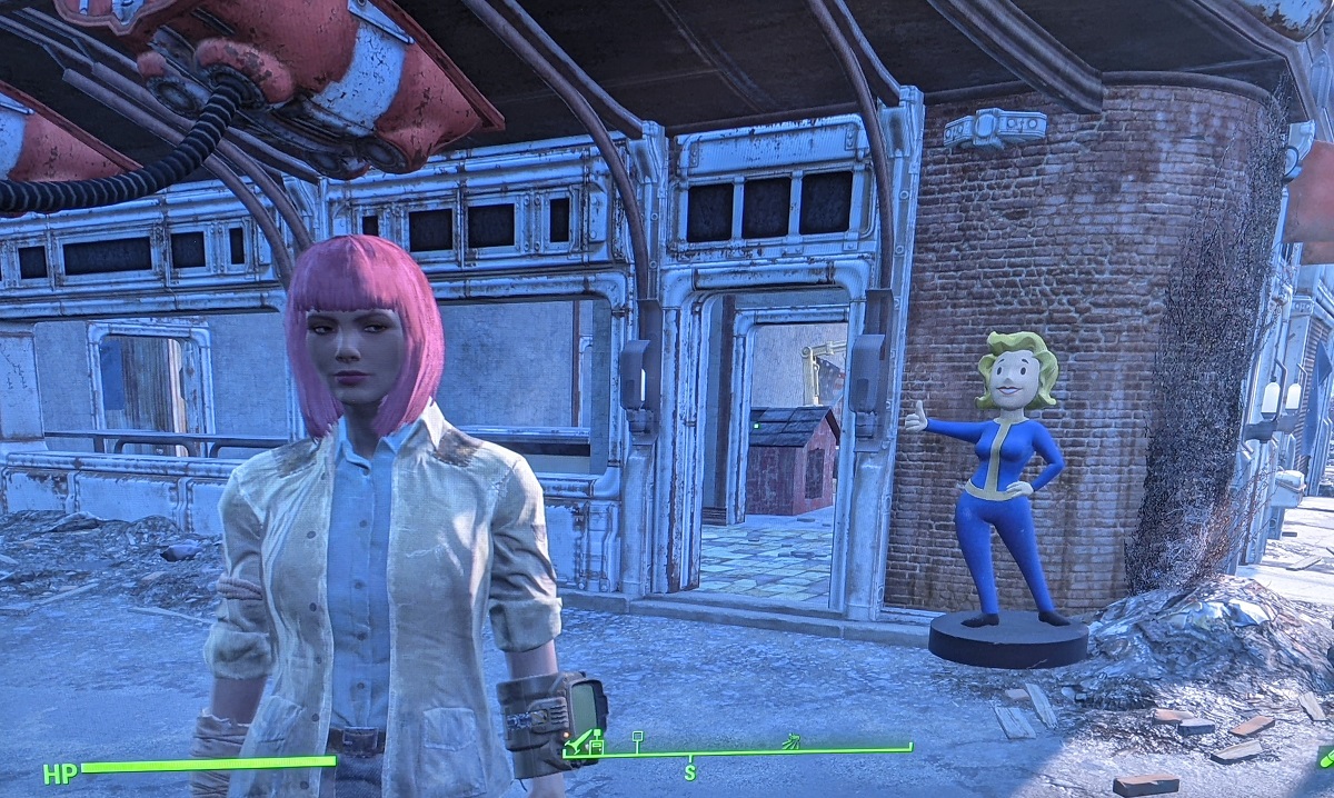 Screencap of Teresa Jusino's player character in 'Fallout 4.' The character is a brown woman with a pink bob haircut with bangs. She's wearing a Minutemen uniform and a pip boy while standing in front of a Red Rocket settlement. Behind her at the door is a Vault Girl statue.