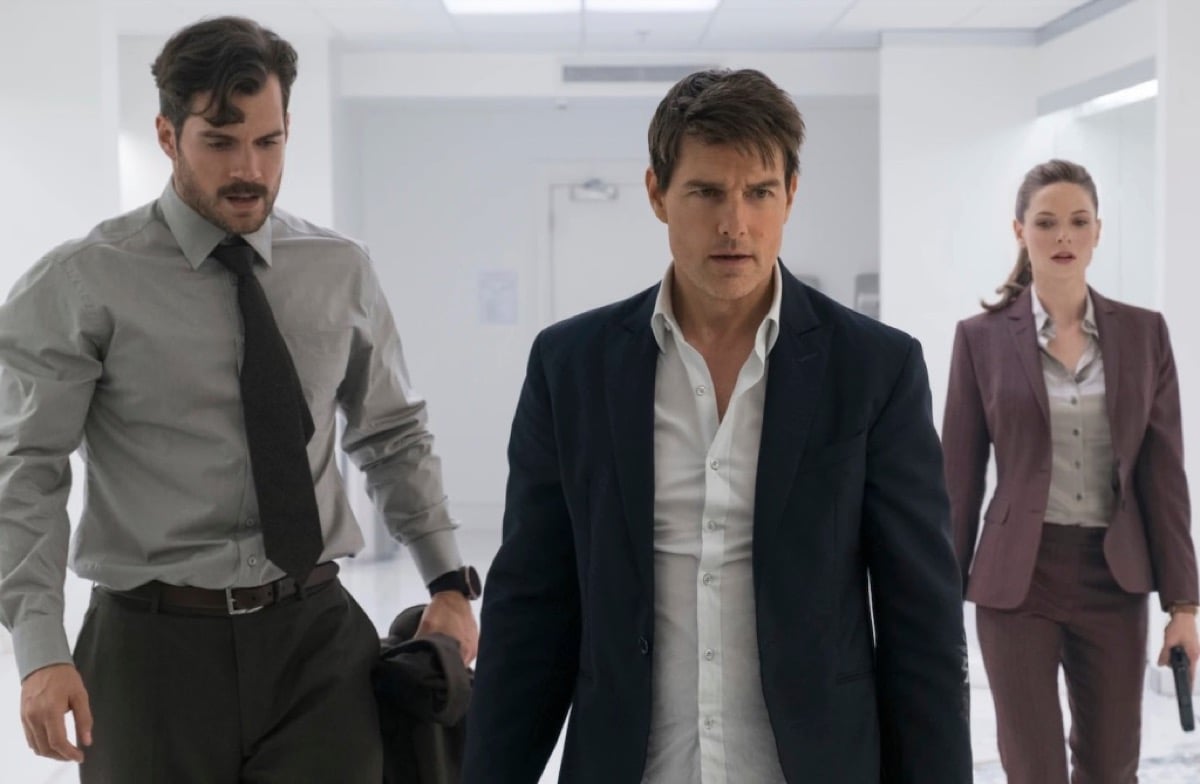 Three says in suits stare intently at a target in a white room in "Mission Impossible - Fallout"